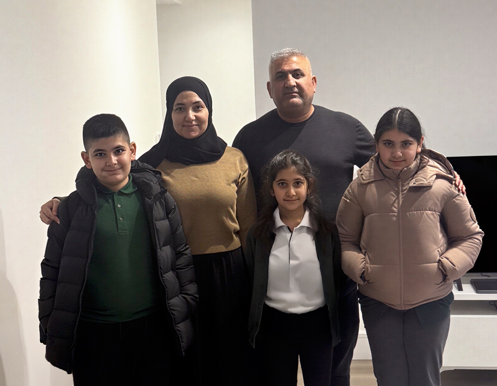 A Flint Housing resident family of five posing together in their new home